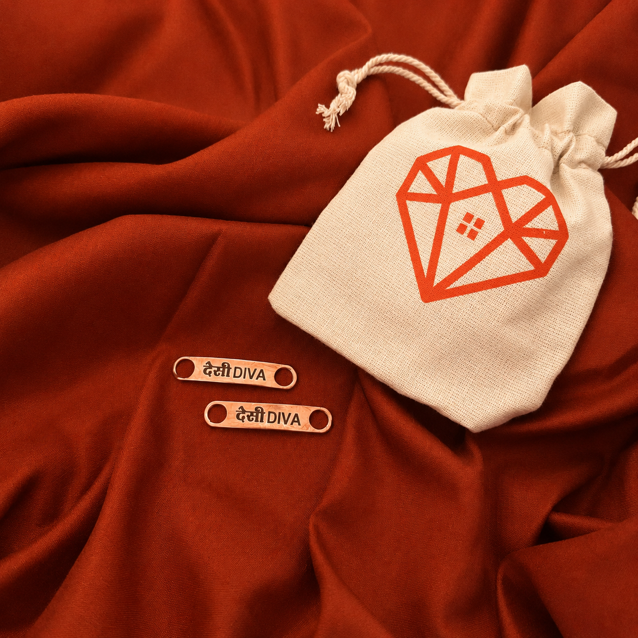 White drawstring bag with Passionize's branding on a red fabric background, featuring 'DESI DIVA' Lace tag.