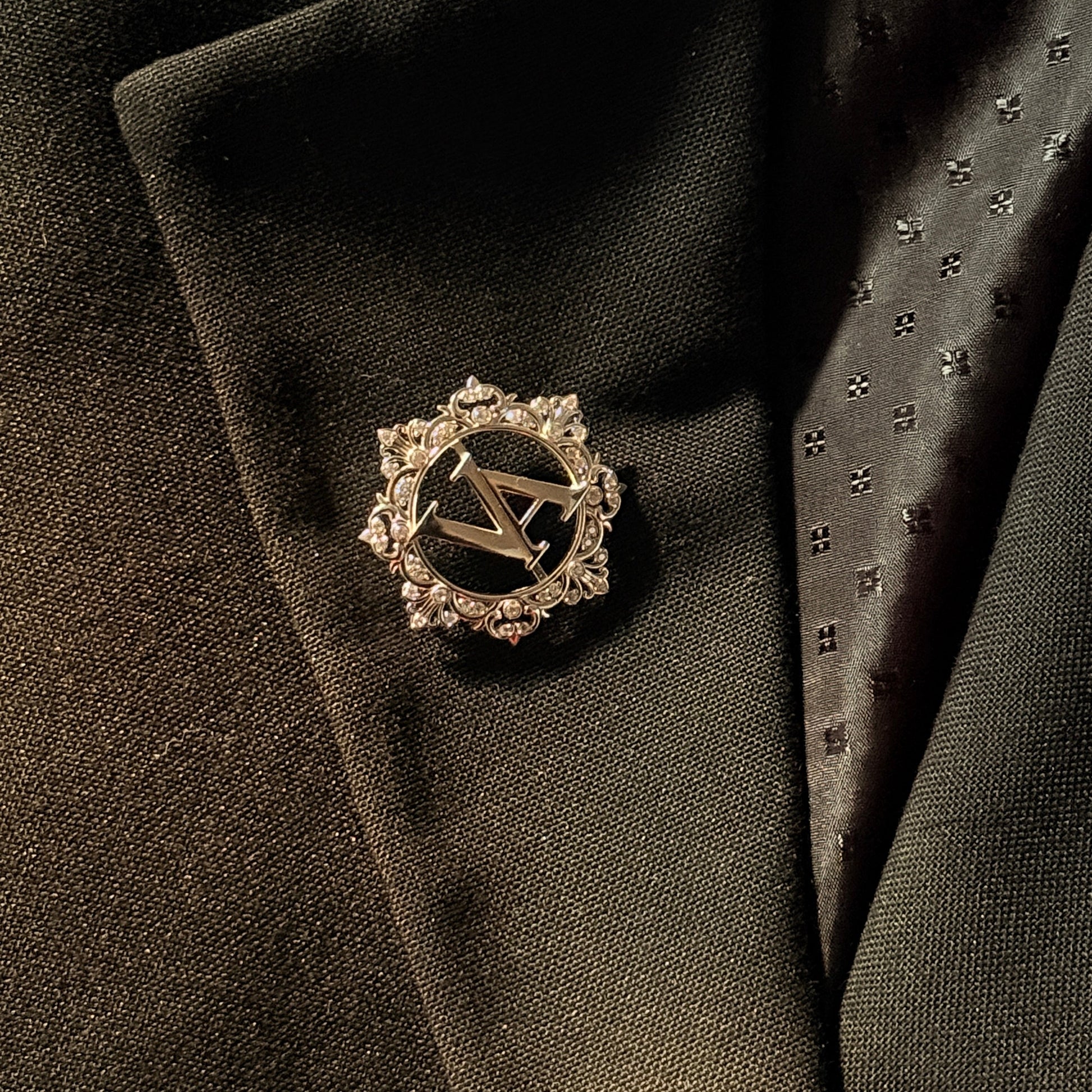 Decorative lapel pin on a dark suit jacket with a tie.