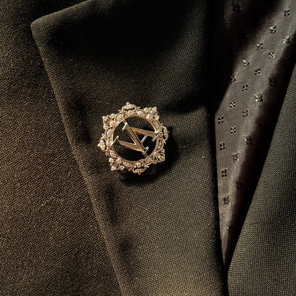 Decorative lapel pin on a dark suit jacket with a tie.